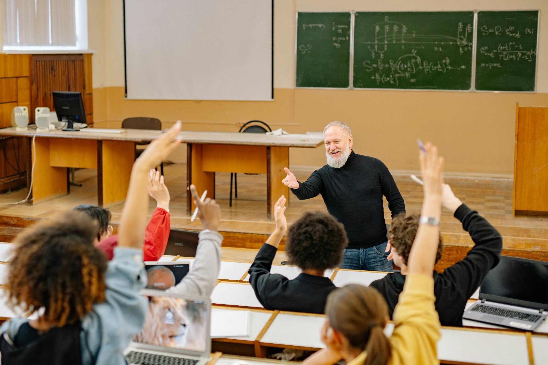 University lecture hall with students raising hands